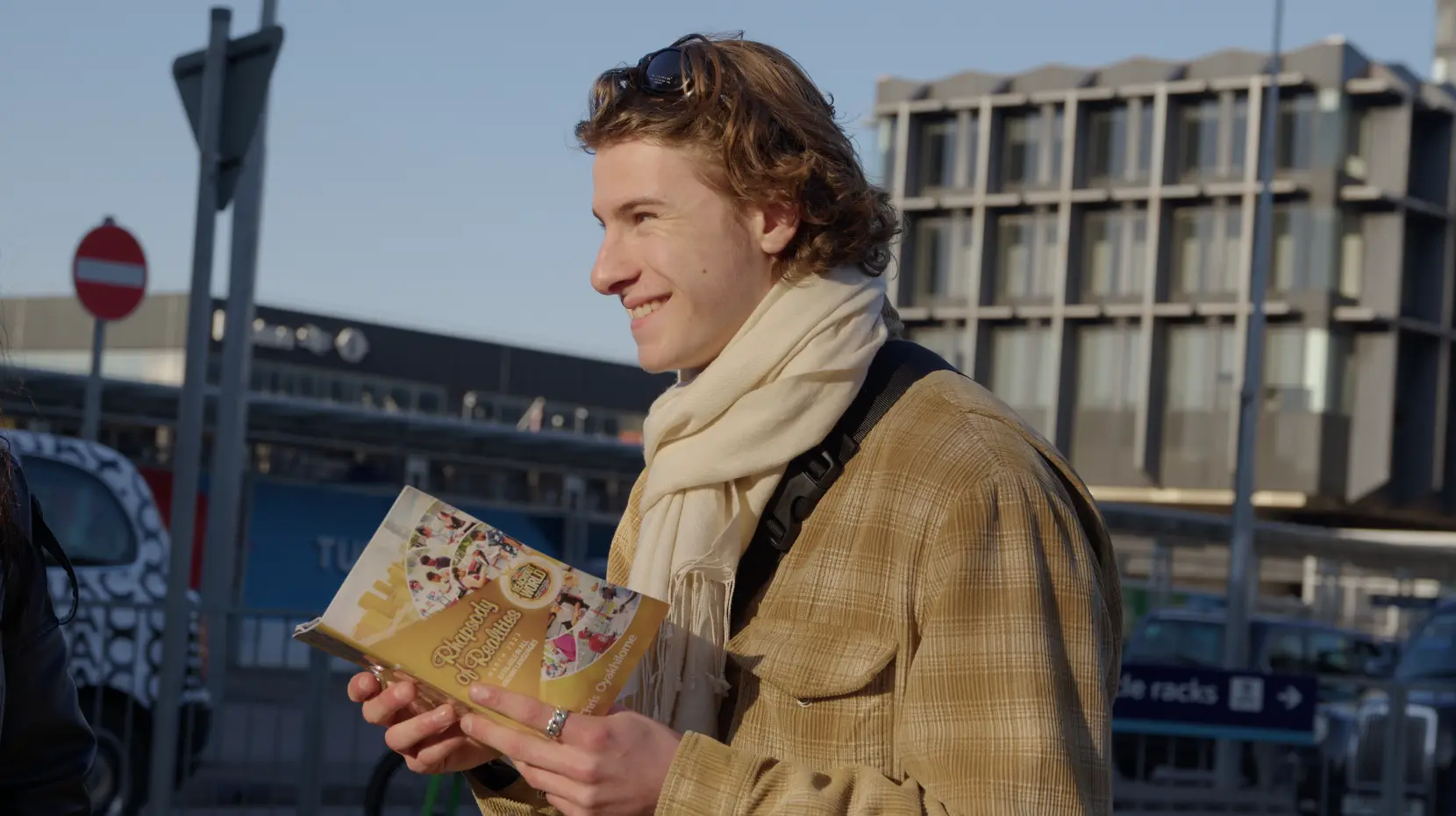 A young man smiles as he reads a copy of Rhapsody of Realities on a city street